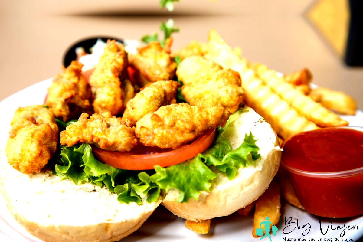 Un sándwich po-boy de ostras fresco y caliente con papas fritas