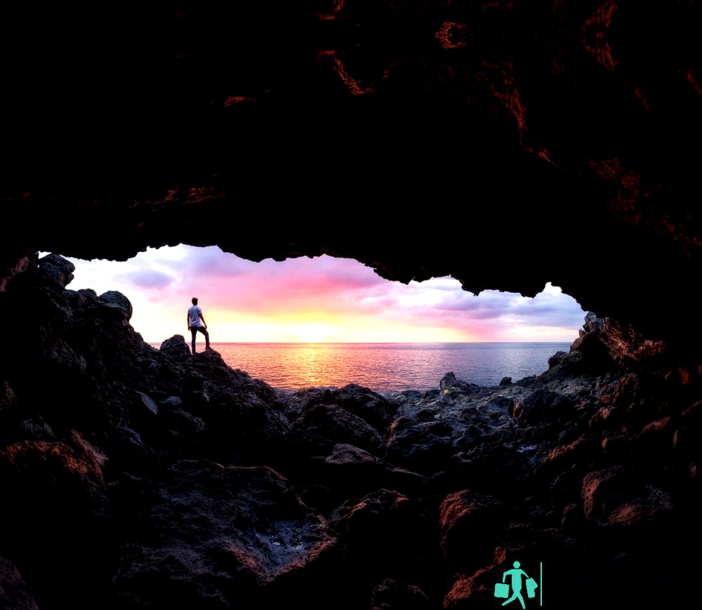 Niño viendo una puesta de sol a través de una cueva en Le Souffleur en Saint-Leu, Isla de la Reunión