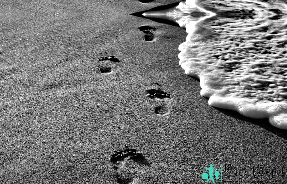 Line of footprints on the beach with wave foam line