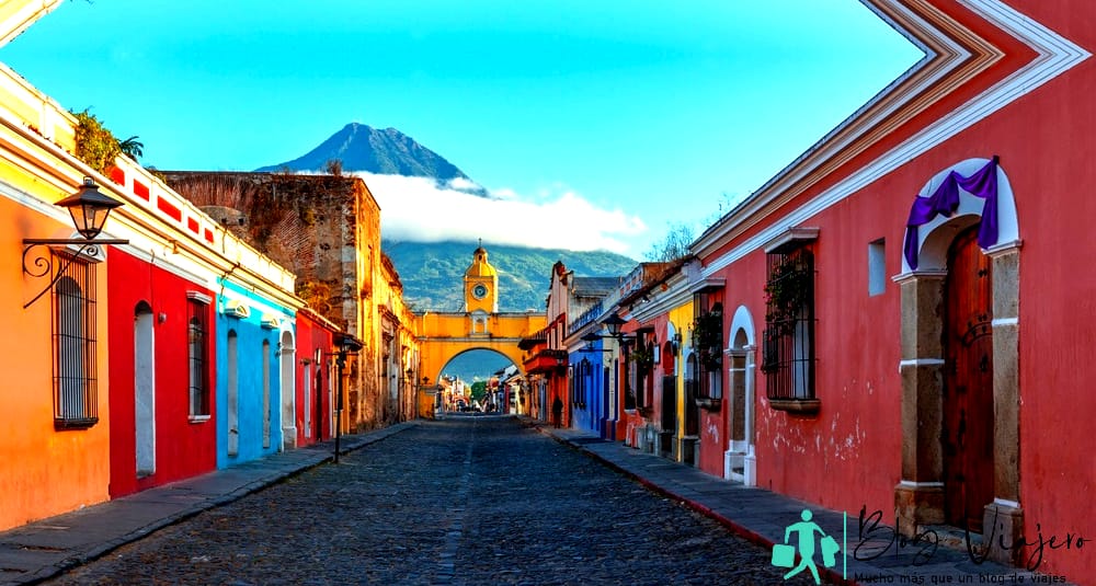 Antigua en marzo - Amanecer panorámico en la calle principal de la ciudad de Antigua con el Arco de Santa Catalina y el Volcán de Agua, Guatemala.