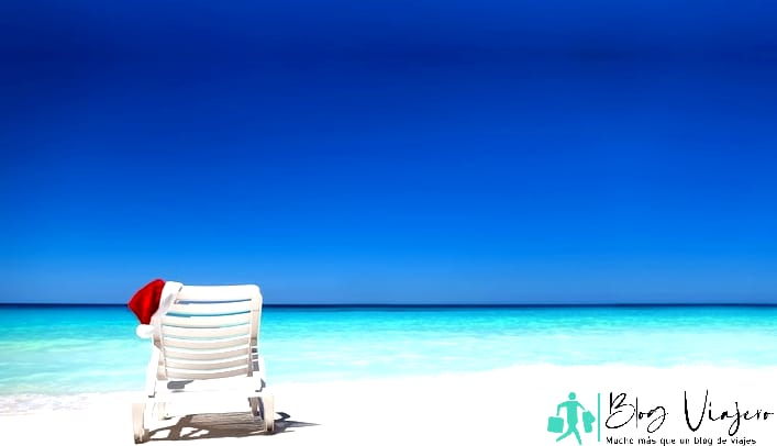 Sombrero de Papá Noel en la tumbona cerca de la tranquila playa tropical con agua turquesa del mar Caribe y arena blanca.  Antigua en diciembre